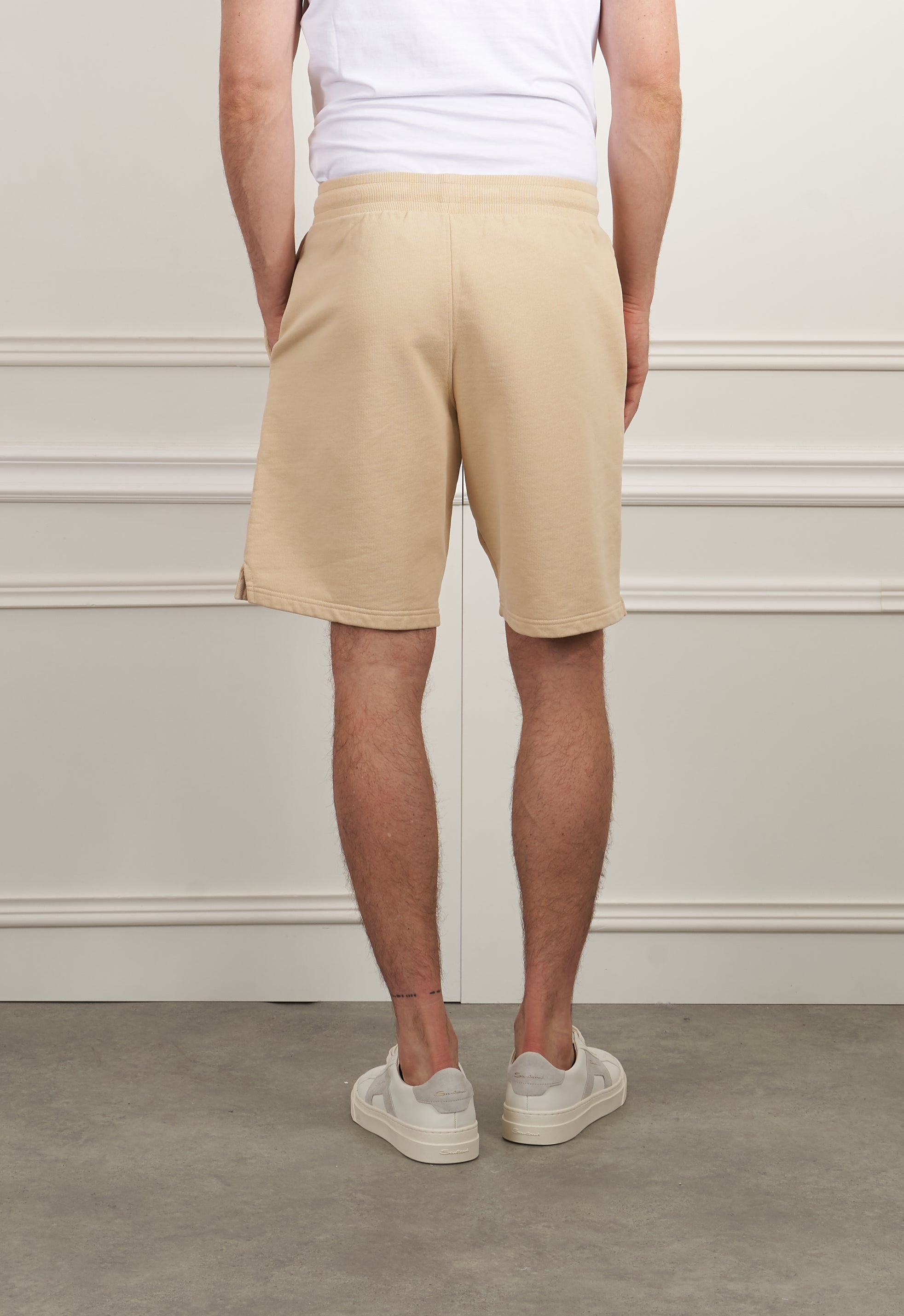 Beige Sweatshorts von AMI Paris, lässige Hose, auf dem Bild mit weißen Sneakers.